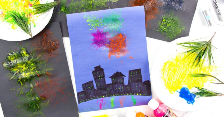 Children’s firework painting made with pine needles, showing colourful bursts of paint and glitter above a hand-drawn city skyline on blue and black paper.