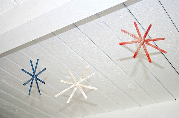 Red, white, and blue firework decorations made from painted craft sticks hanging from the ceiling as a simple DIY kids’ craft.