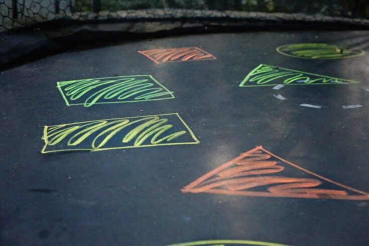 Black trampoline with shapes drawn with chalk on it