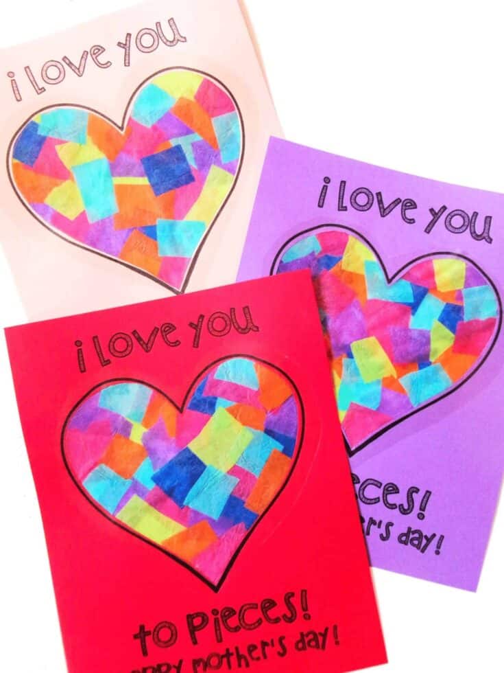 Three handmade Mother's Day cards feature large heart shapes filled with torn tissue paper in bright colors like blue, pink, yellow, and orange. Each card has the phrase “I love you to pieces! Happy Mother’s Day!” written around the heart in playful lettering. The cards are made on red, purple, and light pink construction paper.