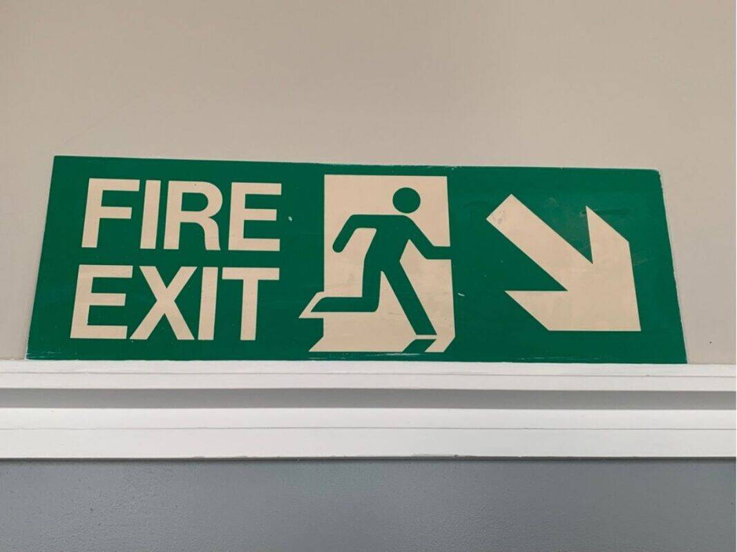 Green sign that says fire exit and an arrow pointing down and right